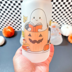 Cute Ghost sitting inside a pumpkin reading a book surrounds by books, leaves, coffee cup, and pumpkins