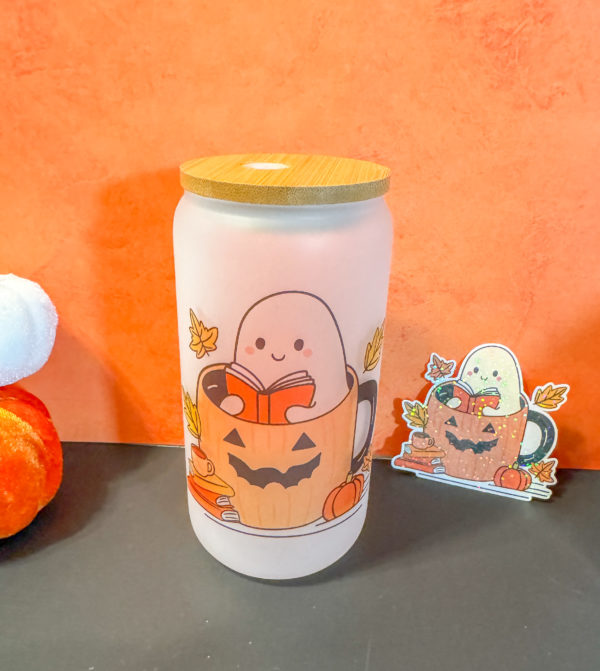 Cute Ghost sitting inside a pumpkin reading a book surrounds by books, leaves, coffee cup, and pumpkins