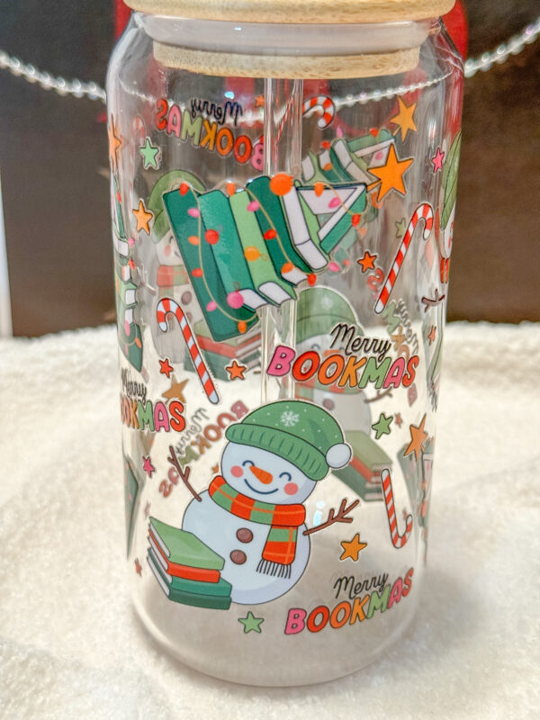 This Merry Bookmas 16oz glass can is the ultimate bookish gift for the holiday season! Designed for book lovers and Christmas enthusiasts alike, this double-sided UV DTF tumbler features a whimsical Christmas tree made of books, a cheerful snowman, candy canes, stars, and festive lights—all in a bright, colorful design that celebrates the coziness of the season.