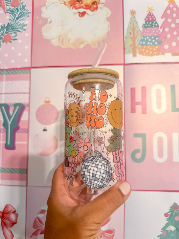 Add a touch of retro flair to your holiday drinkware collection with this 16oz Groovy Christmas glass can! Featuring a double-sided UV DTF design, this unique tumbler brings together a festive disco ball, a Christmas tree adorned with smiley-face string lights, and the playful words "Ho Ho Ho" for a cheerful vibe.