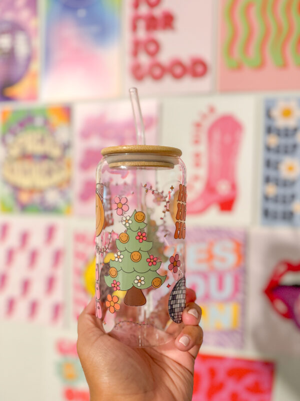 Add a touch of retro flair to your holiday drinkware collection with this 16oz Groovy Christmas glass can! Featuring a double-sided UV DTF design, this unique tumbler brings together a festive disco ball, a Christmas tree adorned with smiley-face string lights, and the playful words "Ho Ho Ho" for a cheerful vibe.